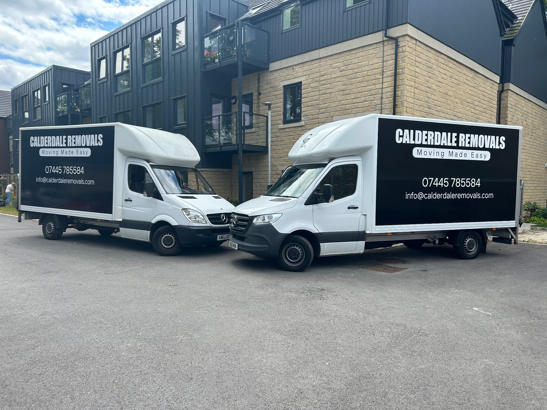 Two removals vans at night outside an apartment building